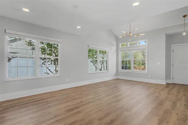 an empty room with wooden floor windows and exposed bricks