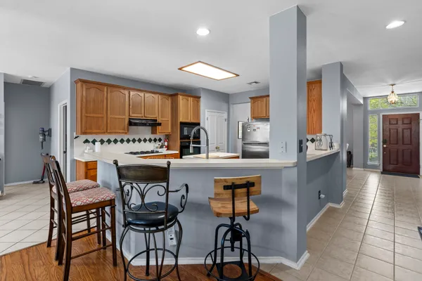 a view of a kitchen with kitchen island a stove a sink a refrigerator and a dining table