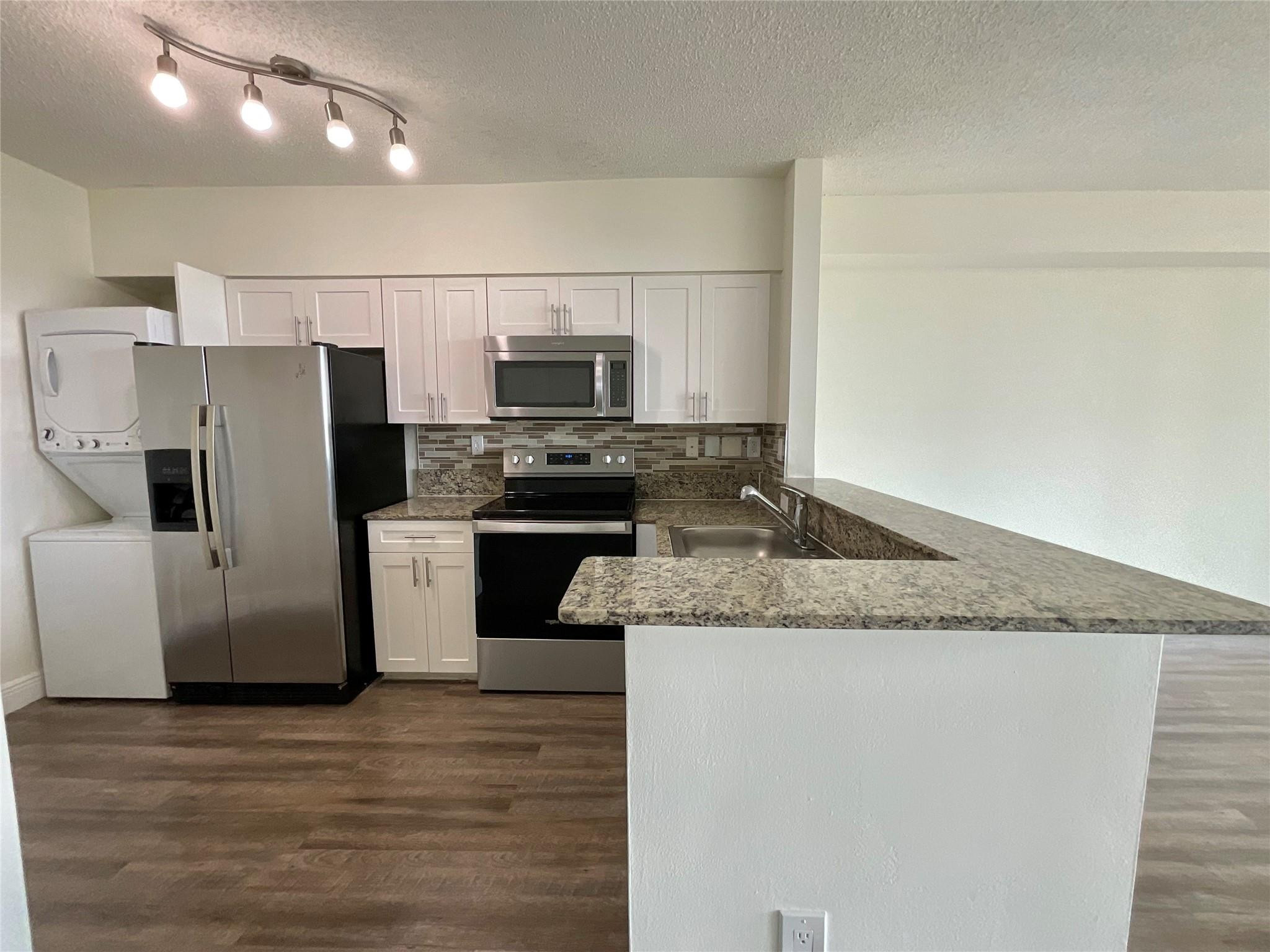 a kitchen with stainless steel appliances granite countertop a refrigerator a stove a sink and a microwave
