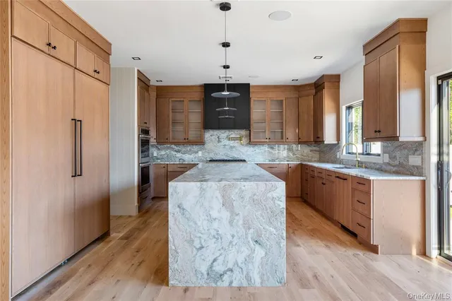 a kitchen with kitchen island granite countertop wooden cabinets a refrigerator a sink a stove and a wooden floors