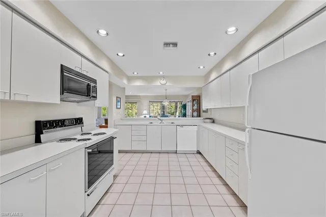 a kitchen with a sink a stove top oven and white cabinets
