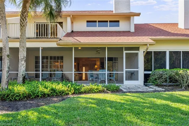 a view of a brick house with a large window and a yard with plants