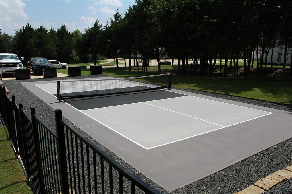 333 Renaissance Lane Heath, TX 75032 - Photo 5 of 35 Dedicated Pickle Ball court with perimeter gravel landscaping, black metal fencing, and surrounding mature trees