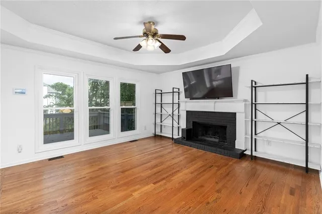a view of an empty room with wooden floor fireplace and a window