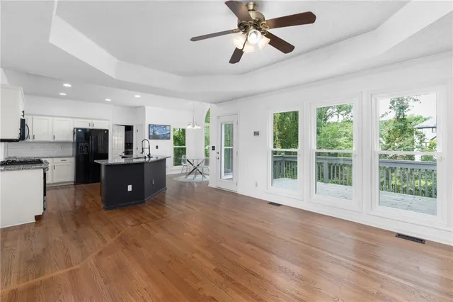 a living room with stainless steel appliances kitchen island granite countertop a refrigerator a stove a sink dishwasher with a dining table and chairs with wooden floor