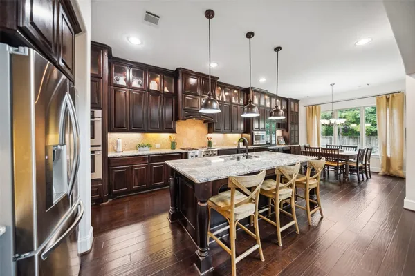 a kitchen with a stove center island wooden floor and a chandelier