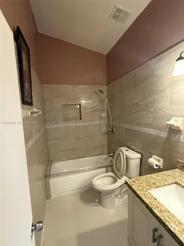 a bathroom with a granite countertop sink a toilet and shower