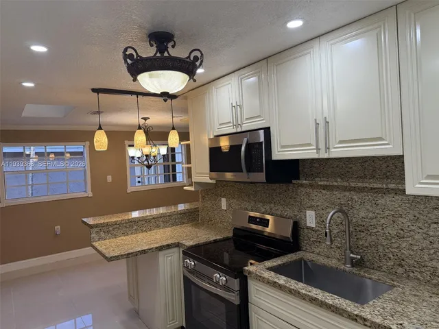 a kitchen with stainless steel appliances granite countertop a sink a stove and a microwave