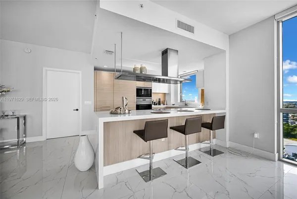 a large kitchen with kitchen island a large counter top space a sink stainless steel appliances and cabinets