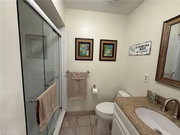 a bathroom with a granite countertop toilet sink and mirror