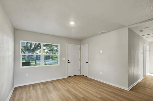 a view of an empty room with wooden floor and a window