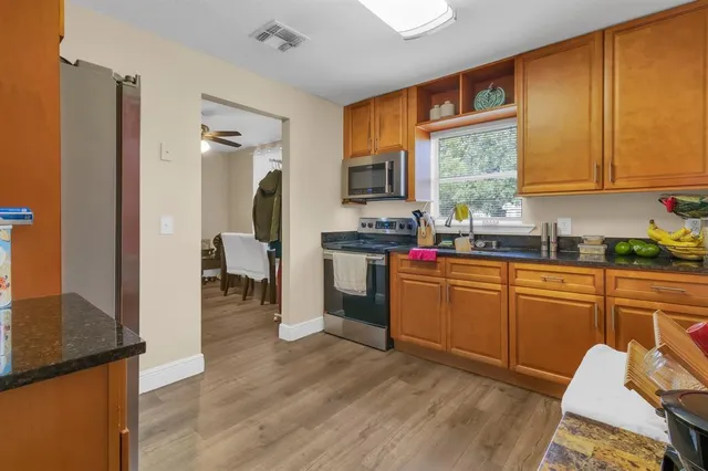 a kitchen with granite countertop a stove a sink dishwasher and a refrigerator with wooden floor