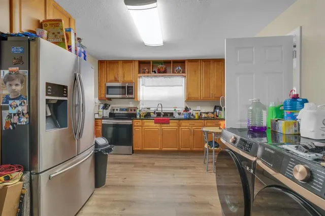 a kitchen with stainless steel appliances granite countertop a refrigerator a sink dishwasher a stove and white cabinets with wooden floor