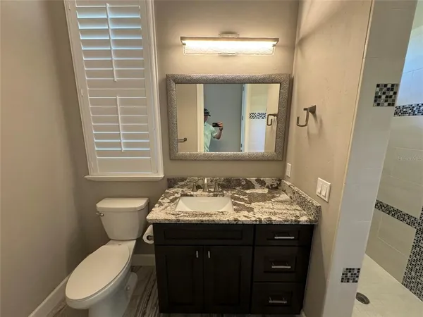 a bathroom with a granite countertop sink toilet and shower