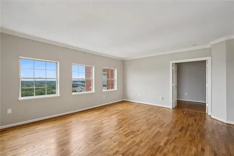a view of empty room with wooden floor and floor to ceiling window