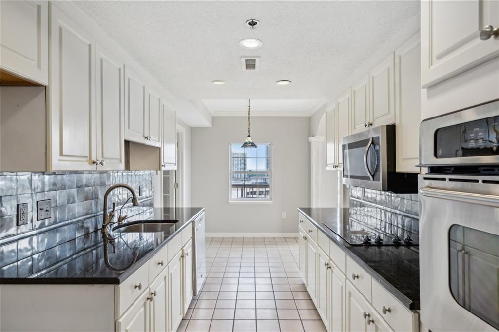 3435 Kingsboro Road Northeast, Unit 1702 Atlanta, GA 30326 - Photo 19 of 35 a kitchen with granite countertop a sink and a stove top oven a refrigerator with wooden floor