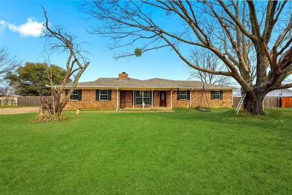 a view of a yard in front of a house with a large tree