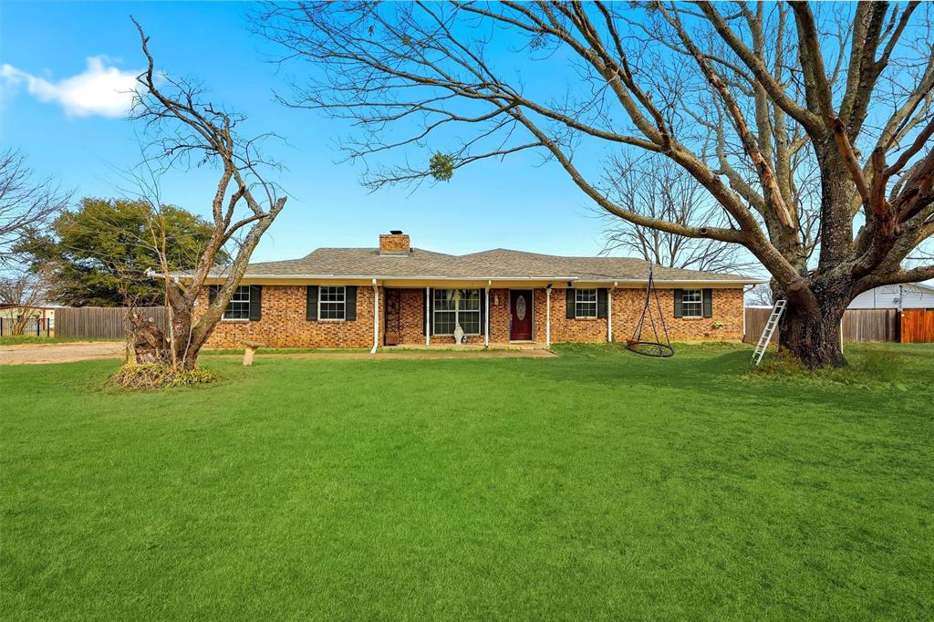 a view of a yard in front of a house with a large tree