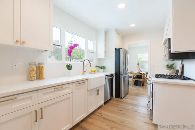 a kitchen with stainless steel appliances white cabinets and wooden floor