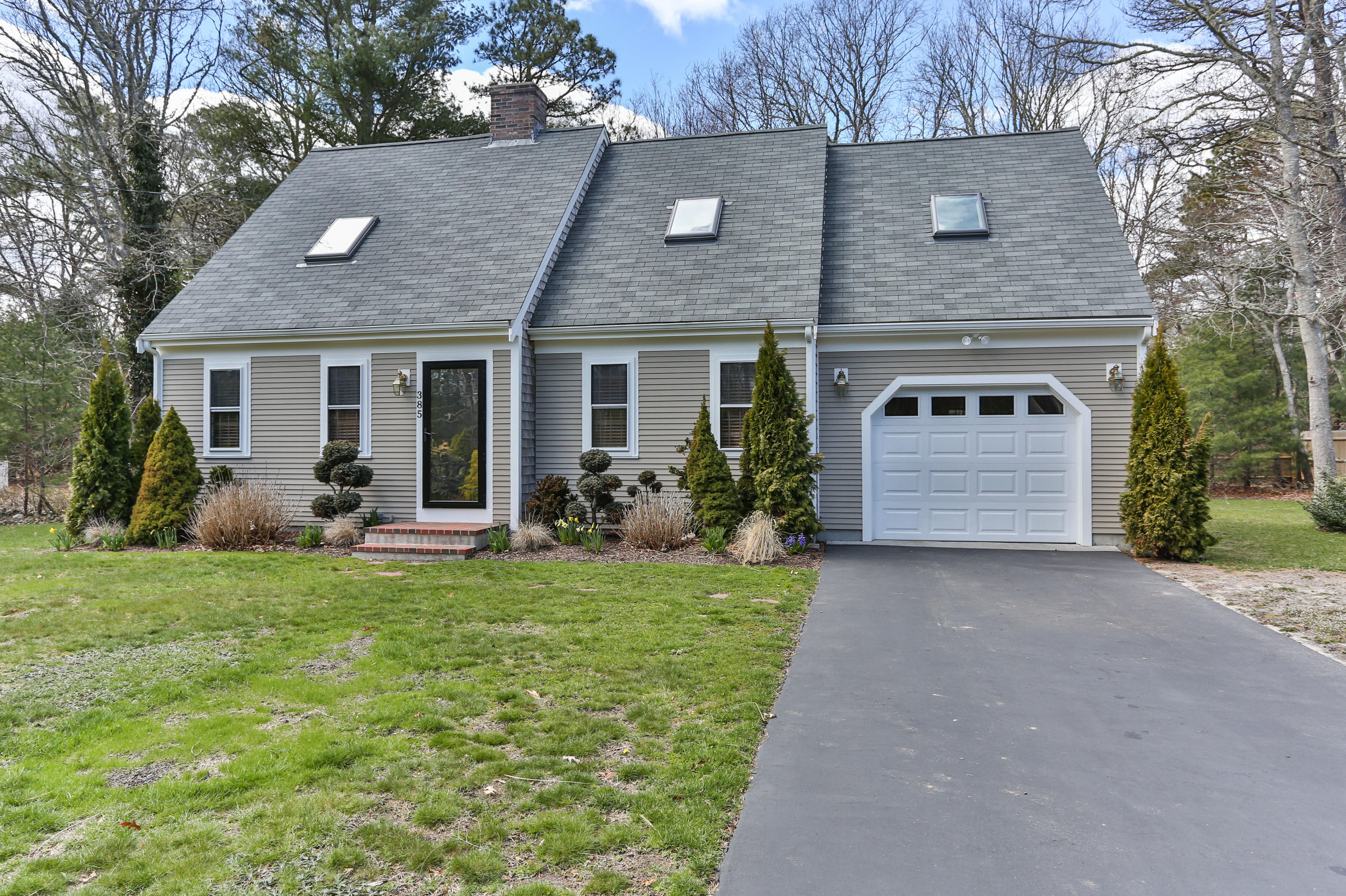 385 Skunknet Road Centerville, MA 02632 - Photo 1 of 32 a front view of a house with a yard and garage