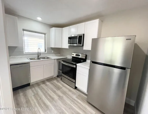 a white refrigerator freezer sitting in a kitchen with white cabinets