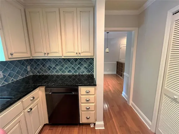 a kitchen with granite countertop white cabinets and black appliances