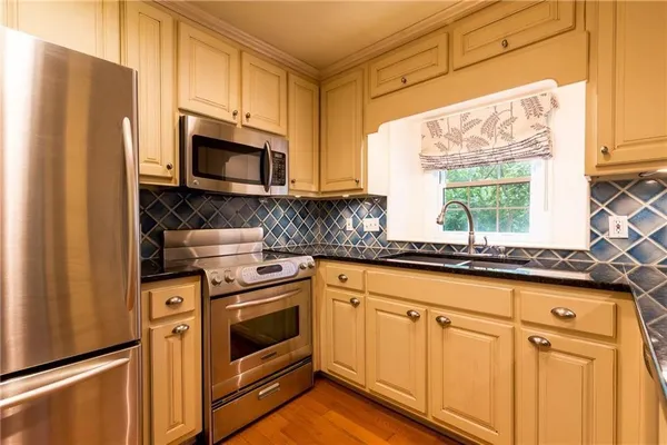 a kitchen with granite countertop white cabinets stainless steel appliances a sink and a window