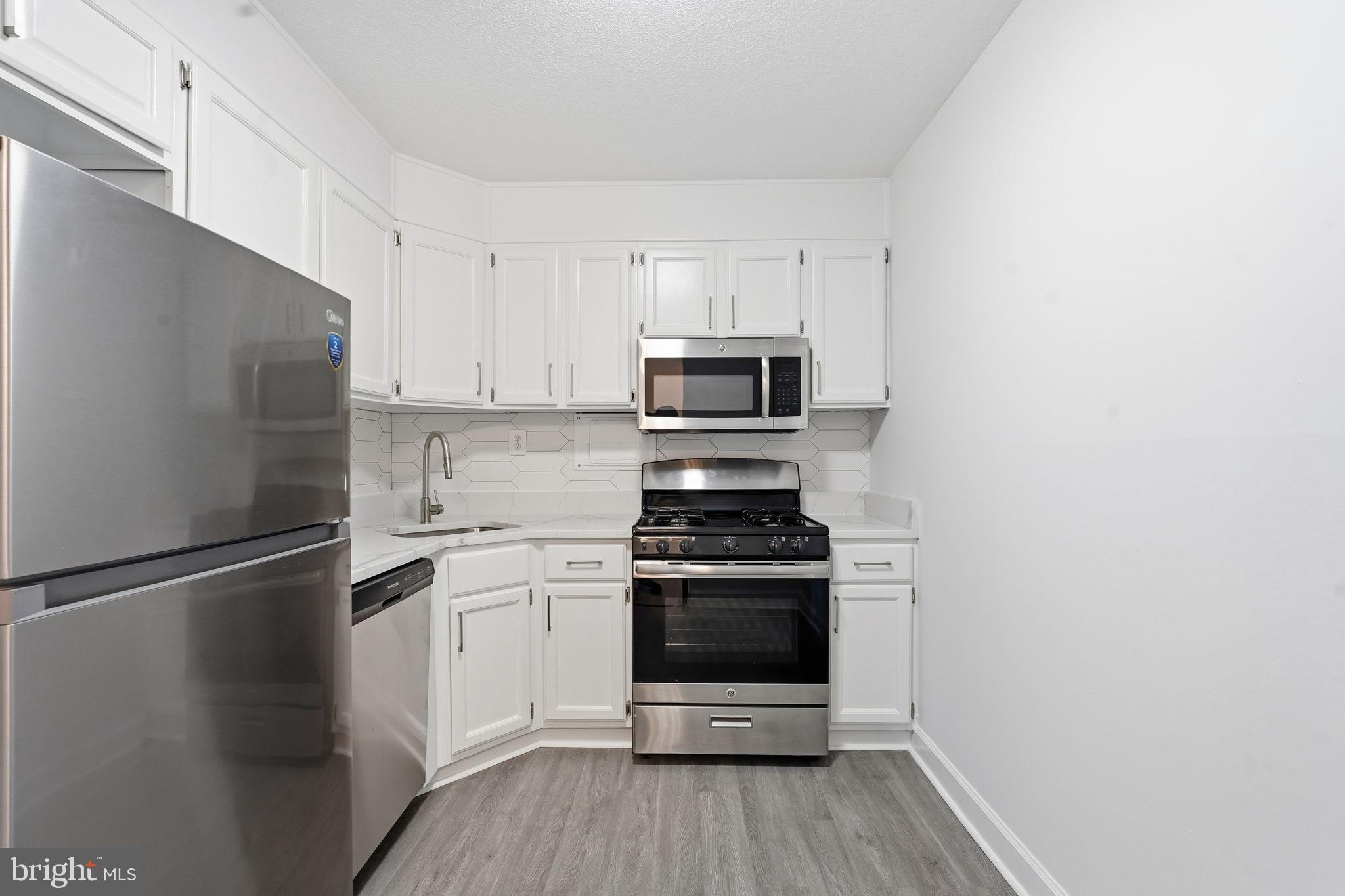 4600 South Four Mile Run Drive, Unit 613 Arlington, VA 22204 - Photo 5 of 24 a kitchen with a refrigerator stove and white cabinets