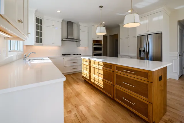 a large kitchen with stainless steel appliances granite countertop a sink a stove and a refrigerator