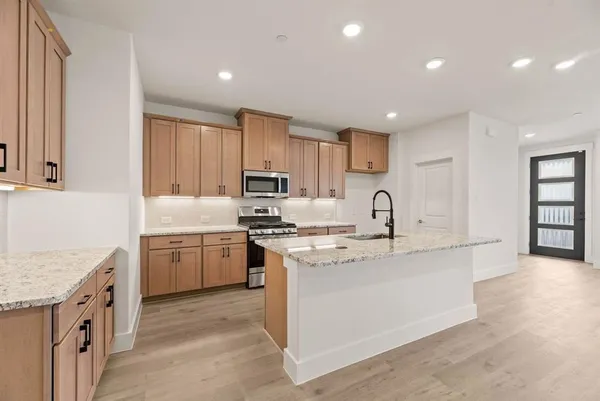 a kitchen with kitchen island granite countertop a sink stove top oven and refrigerator