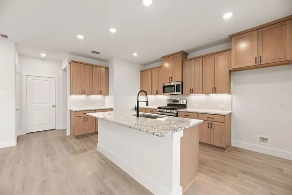 a kitchen with a sink a stove a refrigerator a center island and cabinets