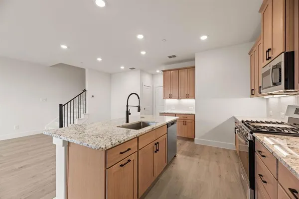 a kitchen with stainless steel appliances granite countertop a sink stove and cabinets