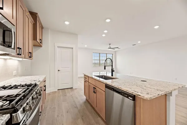 a kitchen with granite countertop a sink stove and cabinets