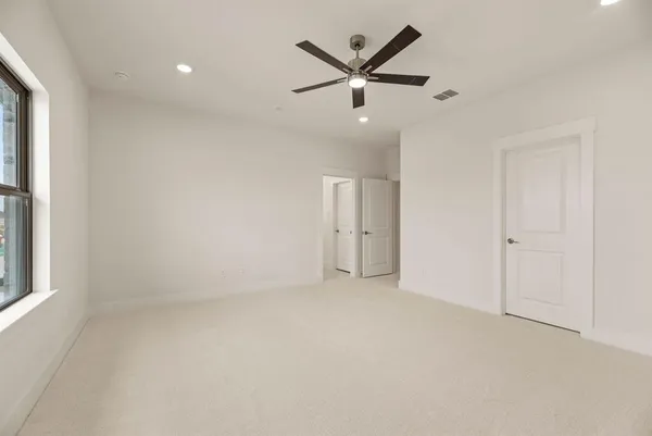 an empty room with ceiling fan and windows