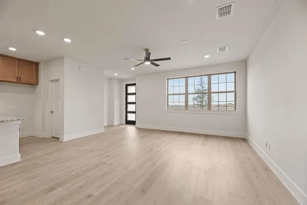 a view of an empty room with a window and wooden floor
