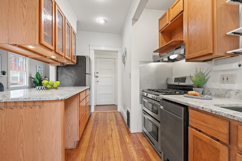 60 Crescent Street, Unit 2 Cambridge, MA 02138 - Photo 10 of 23 a kitchen with stainless steel appliances granite countertop wooden cabinets a sink a stove and a wooden floors