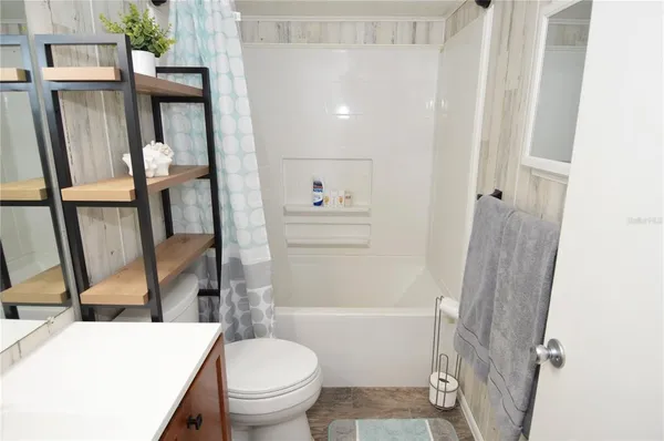 a view of a livingroom with a fireplace a ceiling fan and wooden floor