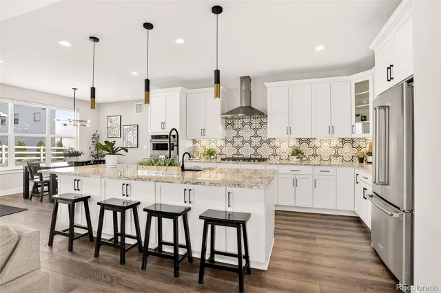 a kitchen with stainless steel appliances granite countertop a table chairs sink and cabinets