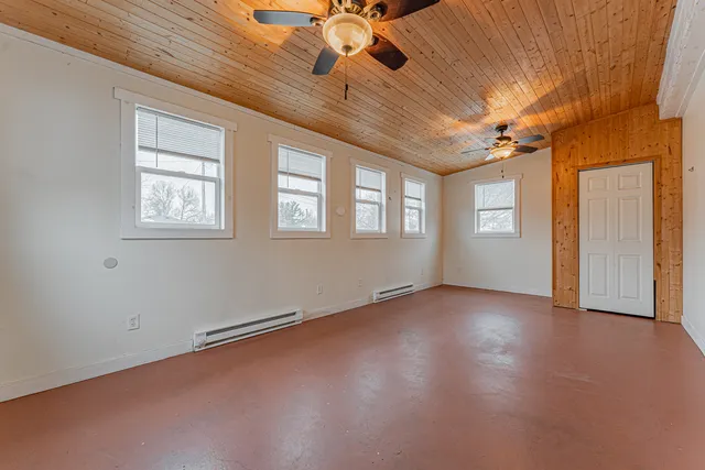 an empty room with chandelier fan and windows
