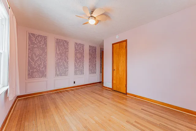 a view of an empty room with window and wooden floor
