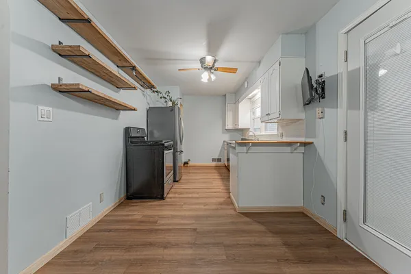 a kitchen with stainless steel appliances granite countertop a refrigerator a sink dishwasher a stove and a refrigerator with wooden floor