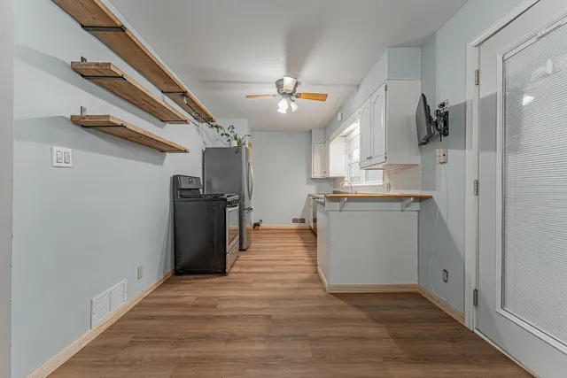 a kitchen with stainless steel appliances granite countertop a refrigerator a sink dishwasher a stove and a refrigerator with wooden floor