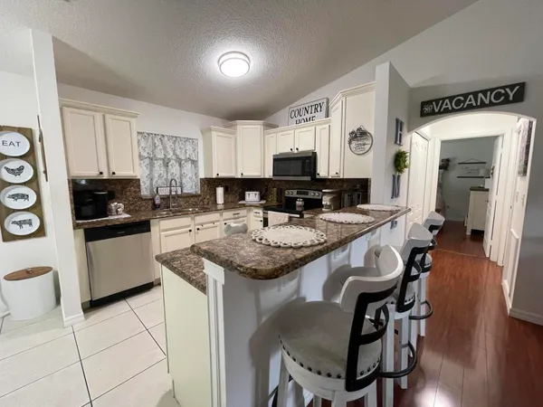 a kitchen with stainless steel appliances granite countertop a sink a stove a refrigerator and cabinets