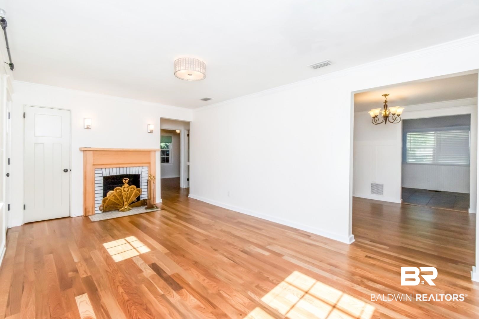 10 South Hathaway Road Mobile, AL 36608 - Photo 5 of 46 Unfurnished living room with a fireplace, light wood-style floors, and a chandelier