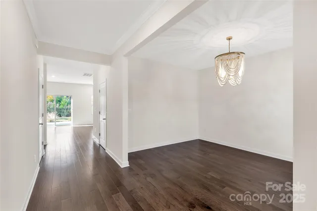 a view of a hallway with wooden floor and a chandelier