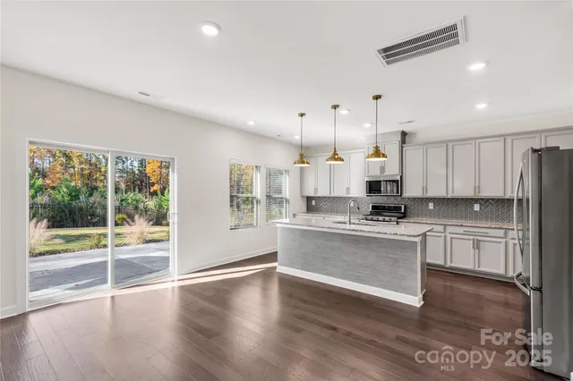 a kitchen with stainless steel appliances kitchen island wooden floors and white cabinets