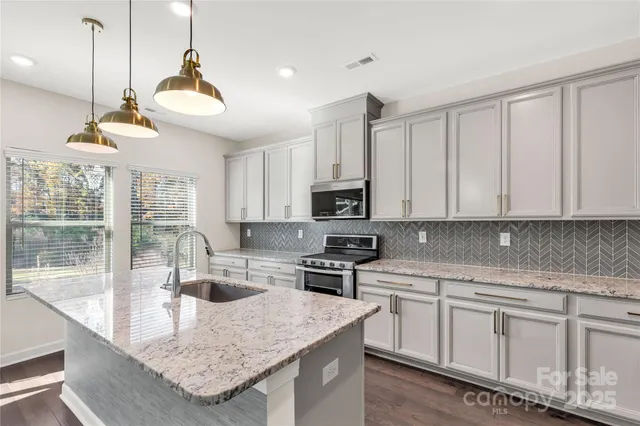 a kitchen with stainless steel appliances granite countertop a sink a stove and a center island