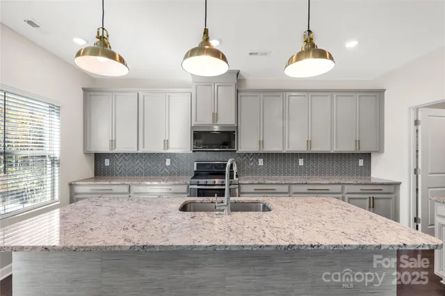 a kitchen with stainless steel appliances granite countertop a sink a stove and a microwave