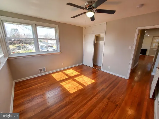 a view of empty room with wooden floor and fan