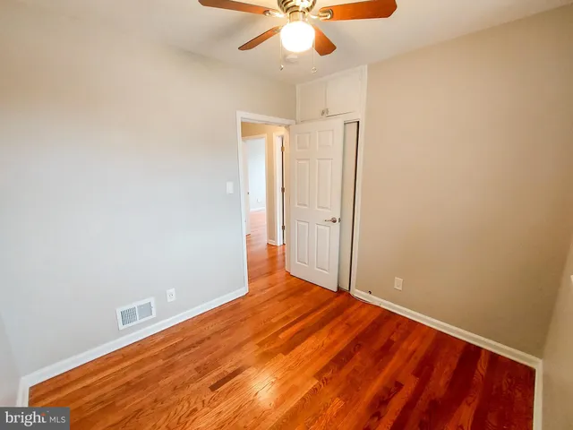 an empty room with a ceiling fan and wooden floor